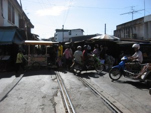 The train market sits on the train tracks until the train comes and then they close their canopies and move their goods to allow the train to pull in and stop. They then sell to the people on the train.